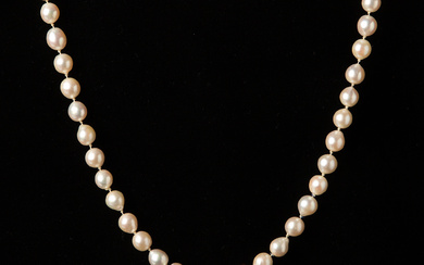 A necklace of cultured pearls with clasps in 18K white gold with brilliant cut diamonds and drop cut emeralds.