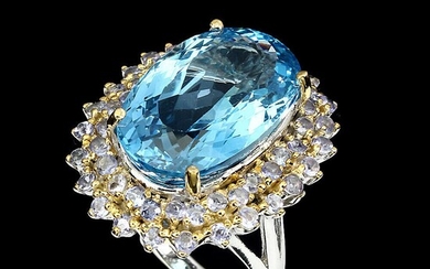 A topaz and tanzanite ring set wiyh an oval-cut tanzanite encircled by numerous circular-cut topazes, mounted in rhodium plated sterling silver.