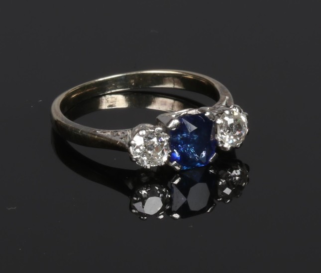 A yellow metal sapphire and diamond three stone ring. The cu...