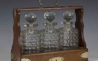 An Edwardian oak and plate mounted three-bottle tantalus, height 32cm, width 36cm (faults).
