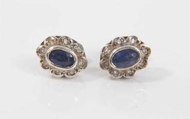 Pair of sapphire and diamond cluster earrings, each with an oval mixed cut blue sapphire surrounded by a border of single cut diamonds. 9.8mm x 7.8mm