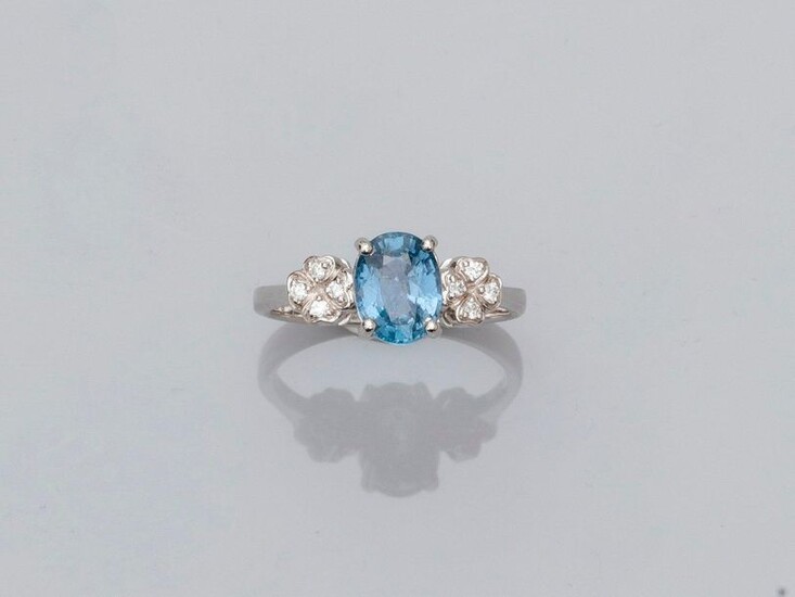 Ring in white gold, 750 MM, set with an oval sapphire weighing 1.74 carat between two florets covered with eight diamonds, size: 52, weight: 3.4gr. rough.