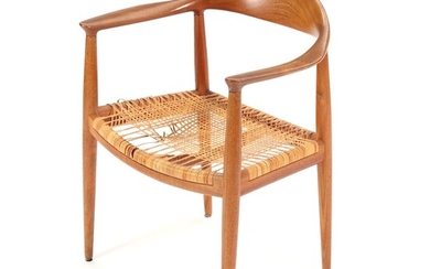 Hans J. Wegner: “The chair”. A teak armchair with woven cane in the seat. Made and stamped by cabinetmaker Johannes Hansen.