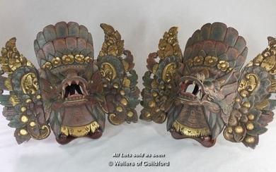 A pair of Balinese masks carved and gilded as mythical beasts.
