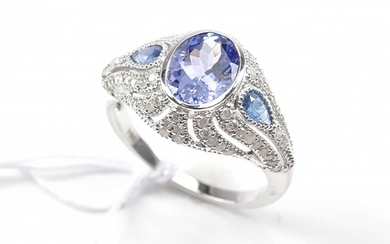 A BELLE EPOQUE STYLE RING SET WITH AN OVAL CUT TANZANITE SHOULDERED BY BLUE TOPAZ, IN A SURROUND OF DIAMONDS, IN 18CT WHITE GOLD, SI...