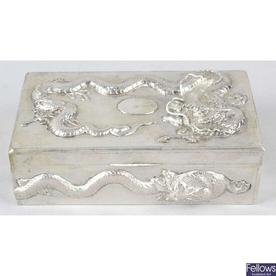 A Chinese export silver table cigarette box decorated with dragons in relief.