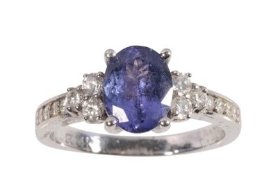 A TANZANITE AND DIAMOND RING the oval-cut tanzanite, flanked...