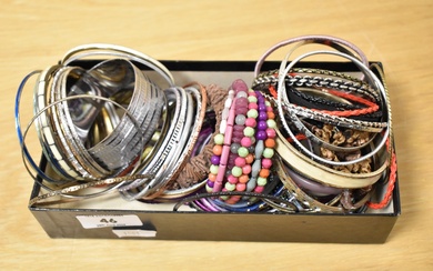 A collection of bangles of various design including a thick engraved buckle style closure bangle