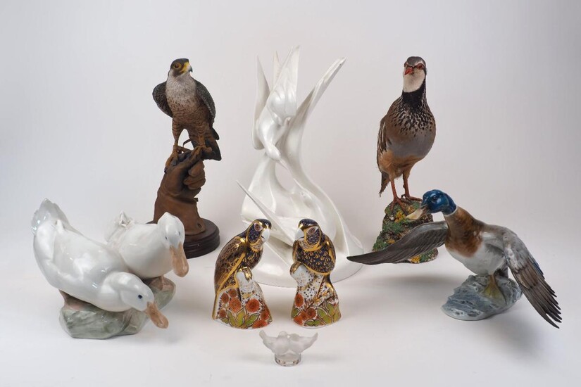 A group of bird sculptures, 20th century, to include a pair of Royal Crown Derby Imari style paperweights as parrots atop a rocky outcrop, with gold stoppers, each 15.7cm high, together with, a Royal Doulton Images white porcelain figure...