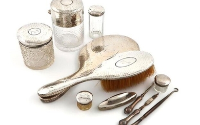 A mixed lot of silver dressing table items, comprising: a large late-Victorian silver-mounted jar, by Mappin and Webb, London 1891, cylindrical form, spot-hammered decoration, and with textured glass, plus a hand mirror, a brush, four toilet jars...