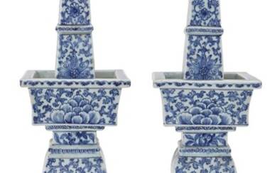 A pair of Chinese blue and white square pricket candlesticks, late Qing dynasty, each painted overall with a leafy scrolling lotus motif, wood stands, 52cm high. (2) Cf. A similar pair was sold at Christie's London, Noble & Private Collections Part...