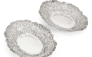 A pair of late Victorian repousse silver dishes, London, 1890, William Comyns & Sons, of shaped oval form, the sides of each dish richly decorated with floral and foliate scroll motifs, 3.2cm high, 22.5cm long, total weight approx. 8.9oz (2)