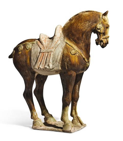 AN AMBER-GLAZED POTTERY FIGURE OF A CAPARISONED HORSE TANG DYNASTY