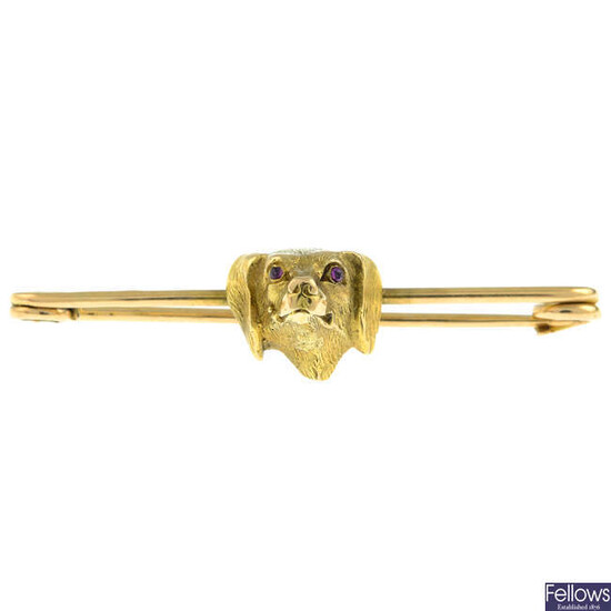 An early 20th century 15ct gold bar brooch of a dog with garnet eyes.