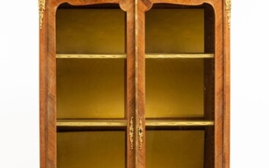 Bibliothèque formant vitrine en marqueterie de bois de placage. Elle ouvre à deux portes vitrées....