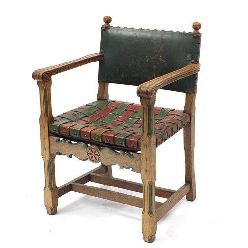 Carved oak open arm chair with red and green leather strap s...