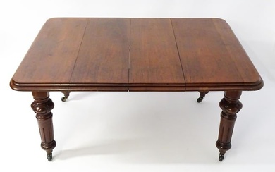 A 19thC mahogany dining table with a moulded top edge raised on four carved legs raised on four