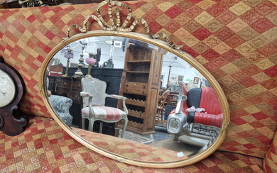 A BEVELLED GLASS OVAL MIRROR WITHIN A RIBBON TOPPED GILT FRAME
