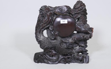A Chinese hardwood panel, carved with a dragon and...