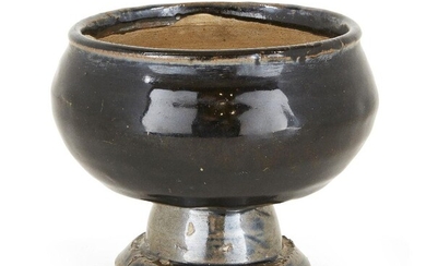 A Chinese stoneware Cizhou-type black-glazed stem censer, Yuan/Ming dynasty, the deep bowl of compressed globular form on a heavily potted stem foot, the exterior covered in a lustrous black glaze that falls down just above the stem foot to reveal...