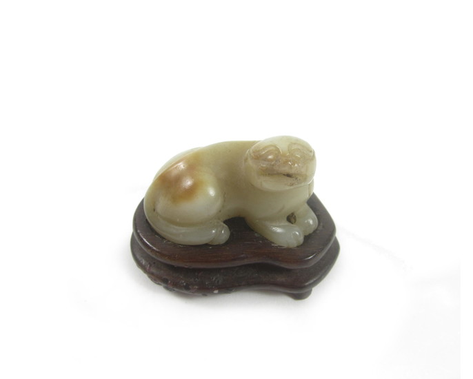 A carved jade lion-dog and wood stand