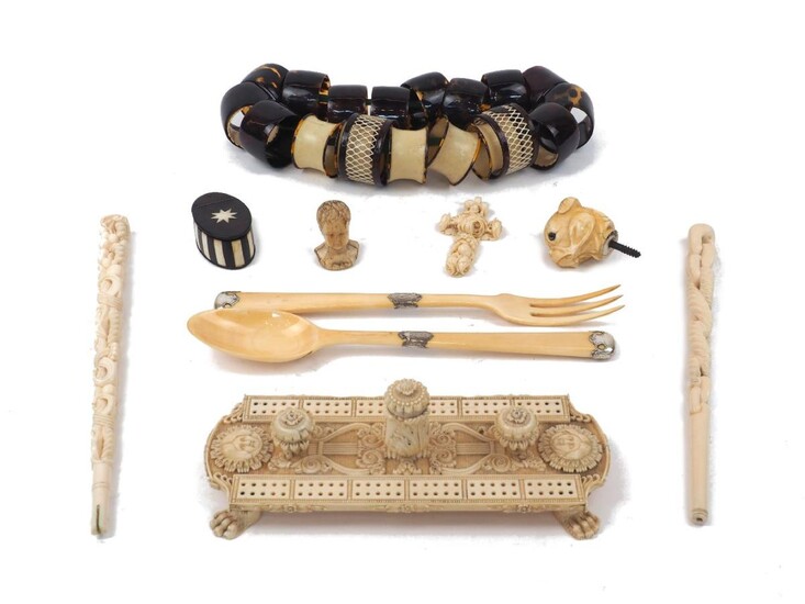 A group of ivory objects of vertu, 19th/early 20th century, to include: a cribbage board with mask and lyre decoration, 23cm long, a serving fork and spoon with French silver mounts dated 1838, 27.5cm long, a cane finial in the form of a dog's...