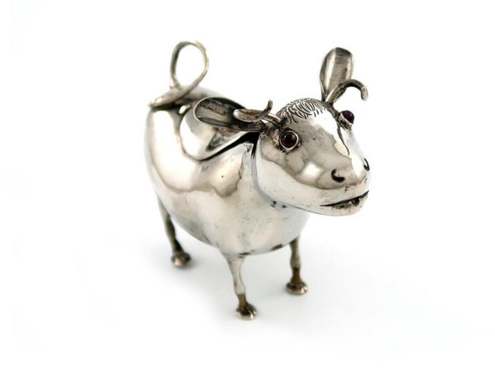 A late 19th century Continental silver cow creamer, probably Dutch or German, modelled in a standing position, the head set with red eyes, the hinged cover set with a fly finial, length 13.5cm, approx. weight 5.9oz.