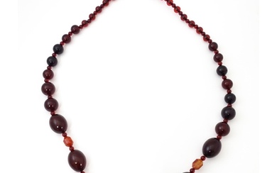 A long bead necklace of graduated cherry amber coloured bead...
