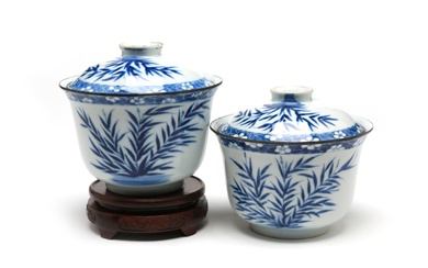 A pair of blue and white porcelain covered bowls painted with bushes all within of plum branches border on a blue ground