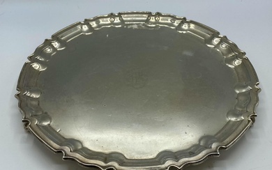 A sterling silver circular tray on three scroll feet...
