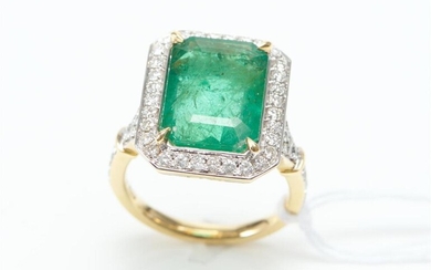 AN EMERALD AND DIAMOND CLUSTER RING IN TWO TONE 18CT GOLD, CENTRALLY SET WITH AN EMERALD CUT EMERALD WEIGHING 6.51CTS, SURROUNDED BY...