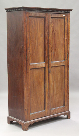 An early 19th century and later mahogany wardrobe, the dentil moulded pediment above two panelled do