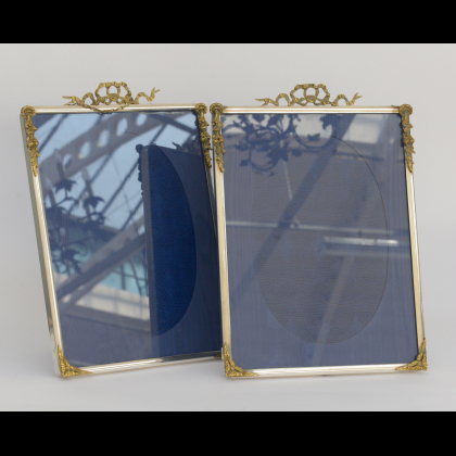 Coppia di cornici portafoto in metallo argentato e fregi in metallo dorato (cm 44x32) (difetti)
