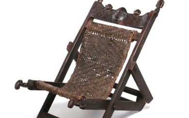 Folding chair of carved patinated wood with woven seat. Mangbetu style. H. 94 cm.