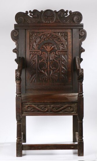 Oak wainscot armchair, early 20th Century, the pediment carve with a face flanked by sea beasts