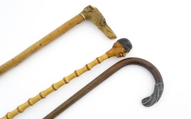 Three 20thC walking sticks / canes comprising one with a carved pommel formed as a folk art head