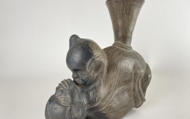 Vase en céramique grise figurant deux singes accouplés. Col évasé. Ancienne étiquette descriptive collée sous...