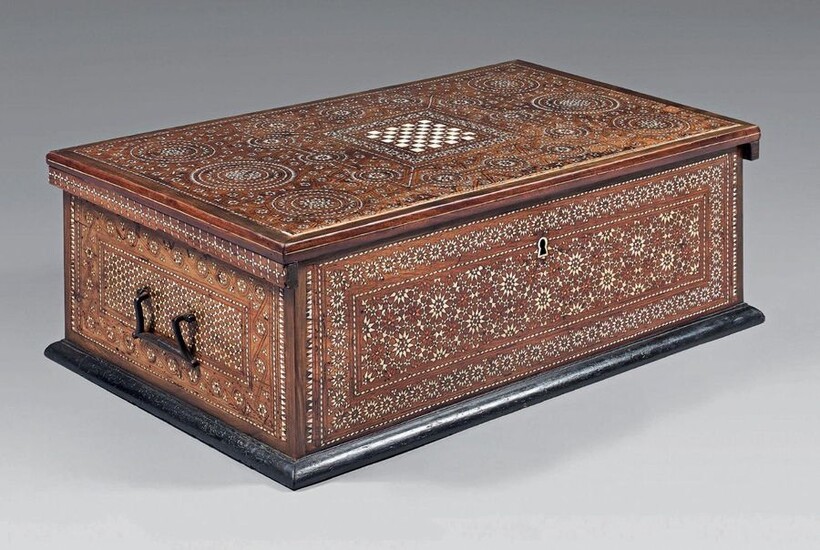 Wooden chest with intarsia decoration of geometrical patterns of star bones, rosettes, friezes ... of rectangular shape, it opens with a lid centered on a checkerboard. Drop handles on the sides.