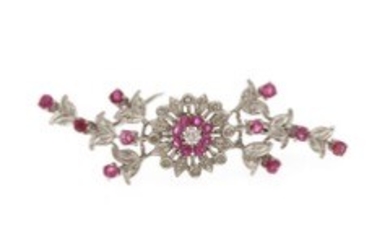 1918/1148 - A ruby- and diamond brooch set with numerous rubies encircled by nine diamonds, mounted in 18k white gold. L. 5.5 cm. Circa 1950s.
