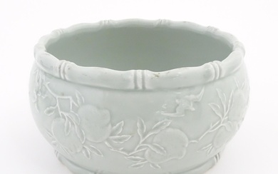 A Chinese celadon planter decorated in relief with peaches a...
