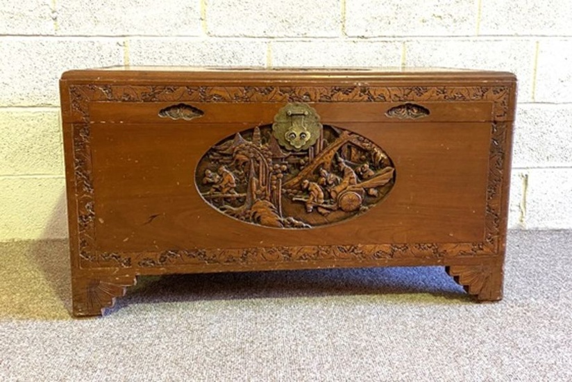 A Chinese style camphor carved chest, the top with carved relief panel depicting travellers
