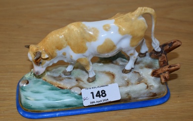 A Continental porcelain cow study, modelled in a naturalistic setting and hand-decorated in