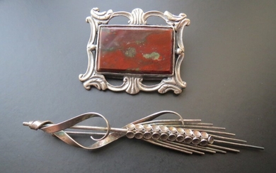 A. Michelsen a.o: A brooch of sterling silver L. 10 cm., and a brooch set with a polished stone presumably jasper, mounted in silver. 4.8×3.9. (2)