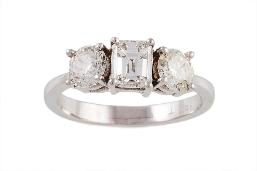 A THREE STONE DIAMOND RING, with an emerald cut diamond of a...
