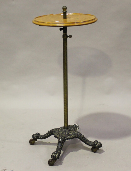 A late Victorian cast iron and oak adjustable wine table with an engraved brass stem and china casto