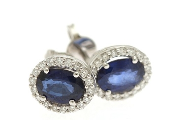 A pair of sapphire and diamond ear studs each set with an oval-cut sapphire encircled by numerous brilliant-cut diamonds, mounted in 18k white gold. (2)