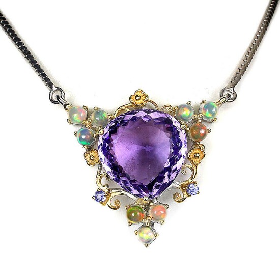 SOLD. An amethyst pendant set with a fancy-cut opal encircle by numerous opals and tanzanites, mounted in rhodium and gold plated sterling silver. L. 49 cm. – Bruun Rasmussen Auctioneers of Fine Art