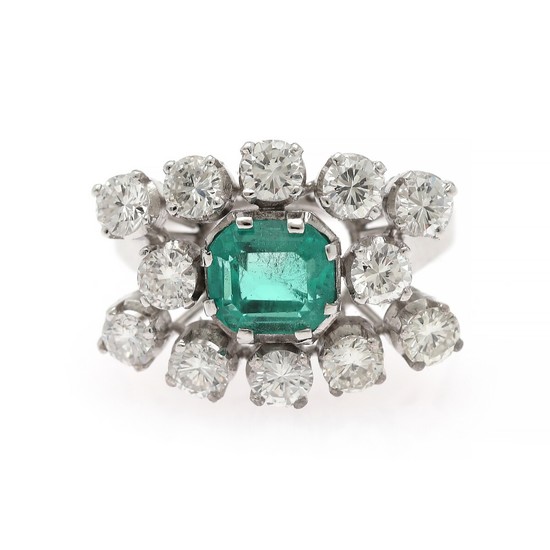 An emerald and diamond ring set with an emerald-cut emerald encircled by numerous brilliant-cut diamonds, mounted in platinum and 18k white gold. Size app. 53.5