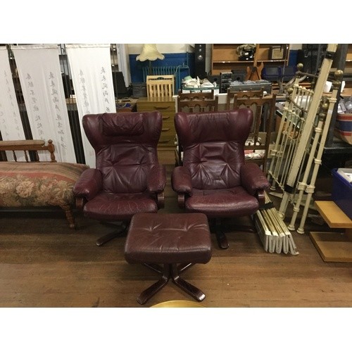 Pair of oxblood leather lounge chairs with matching stool.