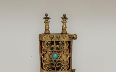 Small miniature torah sefer with its open door and gilded metal parchment.